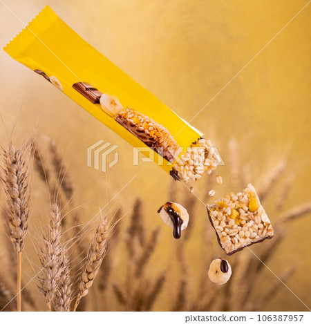 Cereal bar with chocolate and banana, yellow packaging. Against the background of wheat Cereal bar with chocolate and banana, yellow packaging. Against the background of wheat 106387957