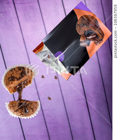 Chocolate muffin with chocolate drops, flies out of the package, purple background. Chocolate muffin with chocolate drops, flies out of the package, purple background. 106387959