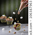 Cooking pistachio cupcakes. Falling ingredients, mint and pistachios. A bag of cream. 106387963
