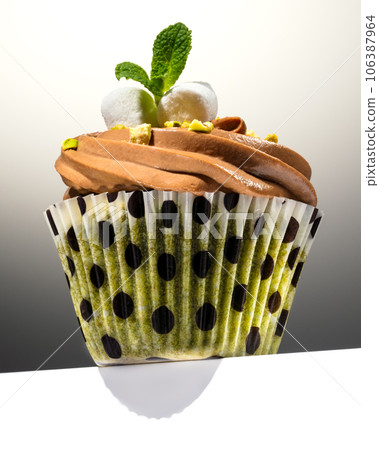 Cupcake with pistachios on the edge of a white table. Marshmallow, mint and pistachios. Close-up. Cupcake with pistachios on the edge of a white table. Marshmallow, mint and pistachios. Close-up. 106387964