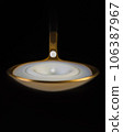 A drop of milk falls into a golden spoon. Black background, macro 106387967