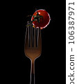 Fork with small tomatoes on a black background 106387971