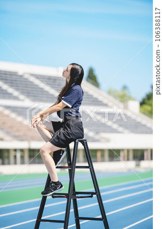 Young woman standing on a stepladder under the blue sky 106388117