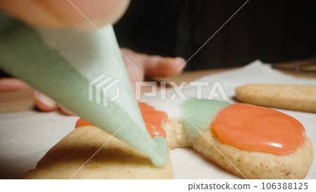I color the gingerbread cookie with green icing from a small pastry bag. I color the gingerbread cookie with green icing from a small pastry bag. 106388125