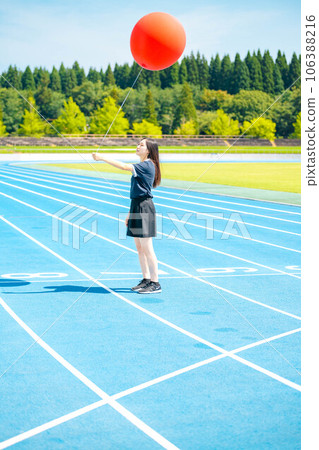 一位女士在盛夏時節在戶外玩得很開心，手裡拿著一個大紅氣球 106388216