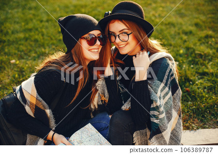 two young stylish girls sitting in the summer city 106389787