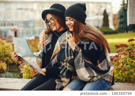 Two young stylish girls travel in an unknown city with a map 106389794