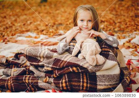 Cute child in a autumn park. Elegant little lady with blonde hair 106389830
