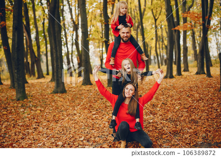 Family in a autumn park. Woman in a red sweater. Cute childrens with parents Family in a autumn park. Woman in a red sweater. Cute childrens with parents 106389872