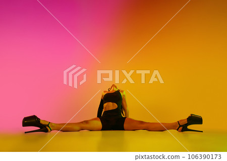 Young woman posing in black bodysuit over gradient pink-orange studio background in neon light Young woman posing in black bodysuit over gradient pink-orange studio background in neon light 106390173