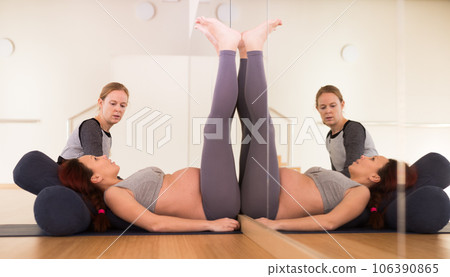 Pregnant woman practices yoga with an instructor 106390865