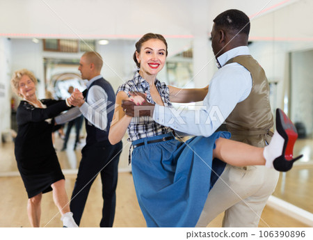 Woman with african man practising charleston dancing Woman with african man practising charleston dancing 106390896