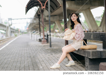 young asian woman traveler with weaving basket waiting for train in train station. Journey trip lifestyle, world travel explorer or Asia summer tourism concept. young asian woman traveler with weaving basket waiting for train in train station. Journey trip lifestyle, world travel explorer or Asia summer tourism concept. 106392150