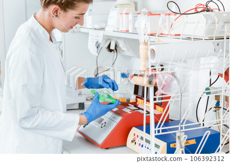 Female researcher using machine for experiment 106392312