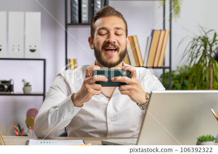 Lebanese businessman plays on smartphone exciting mobile application celebrate winning shooter game 106392322