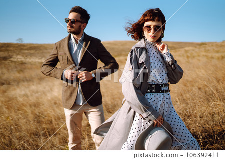 Stylish and loving couple enjoying each other outdoors. Stylish couple walking and hugging. 106392411