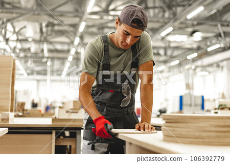 Young carpenter making wood furniture while working in joinery Young carpenter making wood furniture while working in joinery 106392779
