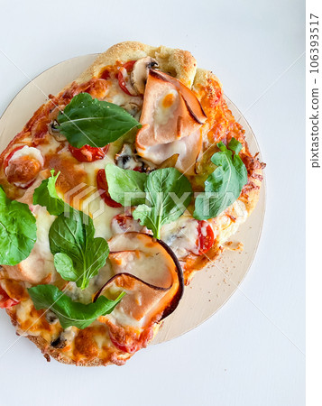 Pizza with ham, mozzarella, tomatoes and leaves on a white background. View from above Pizza with ham, mozzarella, tomatoes and leaves on a white background. View from above 106393517