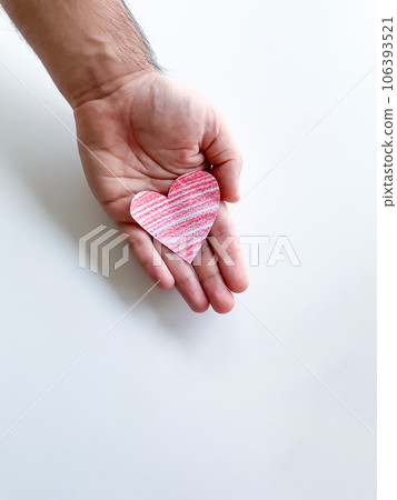 A mans hand holds a red paper heart on a white background. Empty space for an inscription. The concept of manifestation of love. A mans hand holds a red paper heart on a white background. Empty space for an inscription. The concept of manifestation of love. 106393521