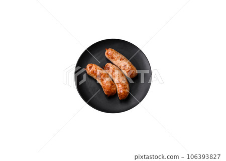 Delicious juicy grilled sausages with salt, spices and herbs on a ceramic plate Delicious juicy grilled sausages with salt, spices and herbs on a ceramic plate 106393827