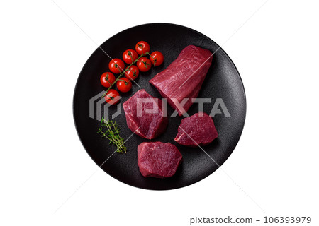 Juicy raw beef with spices, salt and herbs on a dark concrete background Juicy raw beef with spices, salt and herbs on a dark concrete background 106393979