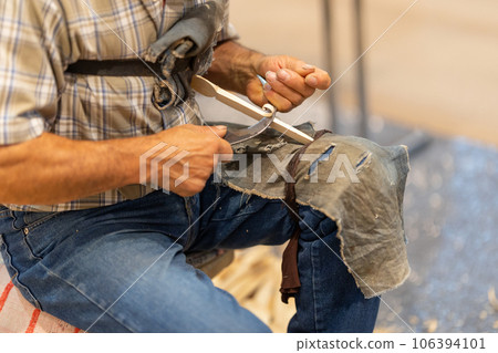 A man planing a wooden figurine using a sickle 106394101