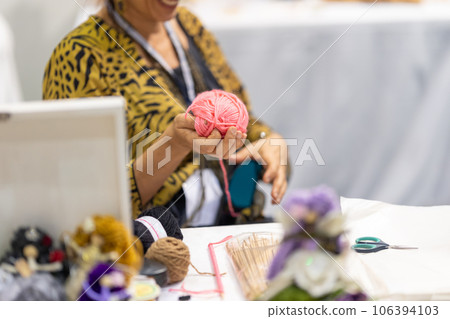 An elderly woman holds a skein of yarn in her hand 106394103