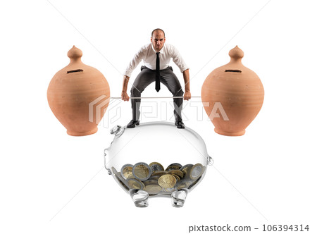 Powerful and determined  businessman trains with a barbell with piggy banks 106394314