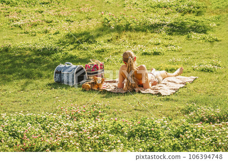 Girl relaxing with her dog on picnic on the green grass, summer day Girl relaxing with her dog on picnic on the green grass, summer day 106394748