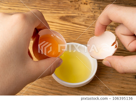 Broken Egg in Hand, Raw Yolk and White Separation, Cracked Brown Shell, Fresh Broken Organic Chicken Eggs 106395136