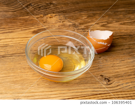 One Broken Egg in Black Bowl, Raw Yolk and White, Fresh Broken Organic Chicken Egg One Broken Egg in Black Bowl, Raw Yolk and White, Fresh Broken Organic Chicken Egg 106395401
