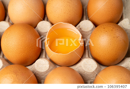 Whole Chicken Eggs and One Broken Closeup, Broken Egg in Carton Pack, Brown Hen Eggs Container Whole Chicken Eggs and One Broken Closeup, Broken Egg in Carton Pack, Brown Hen Eggs Container 106395407