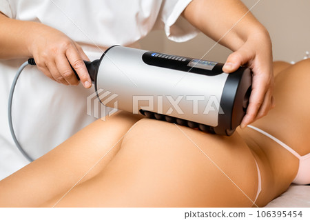 Specialist uses a professional fat burning device to perform an abdominal massage with expertise 106395454