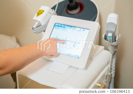 Close up cosmetologist hand tries to adjust settings of laser depilation. Close up cosmetologist hand tries to adjust settings of laser depilation. 106396413