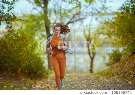 stylish woman in fitness clothes in park jogging 106396743