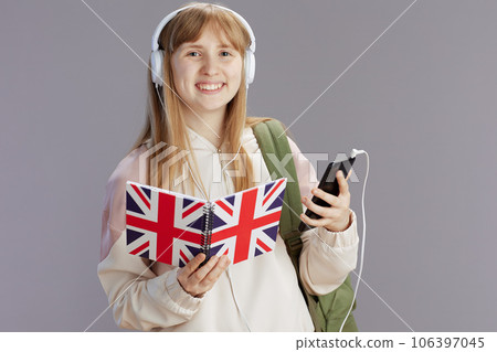 smiling trendy school girl in beige tracksuit with backpack 106397045