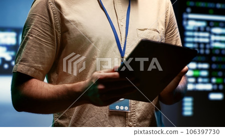 Engineer doing annual maintenance, helping extend data center hardware life span and avoiding downtime. Expert monitoring server infrastructure components using tablet, close up 106397730