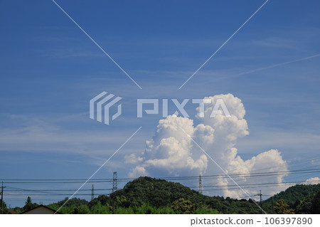 Cumulonimbus clouds and power lines rising from the other side of the mountain 106397890