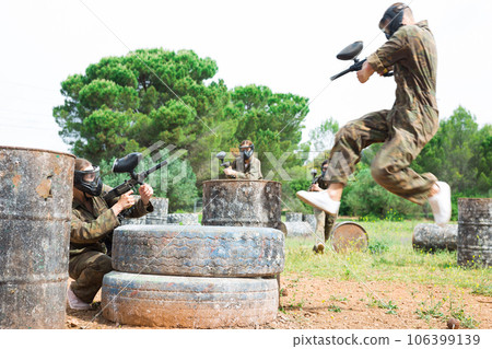 Two active opposing teams with guns playing paintball Two active opposing teams with guns playing paintball 106399139