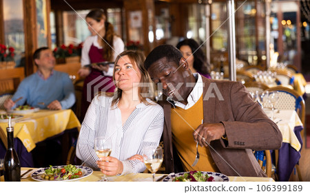 Husband and wife eating and talking in restaurant Husband and wife eating and talking in restaurant 106399189