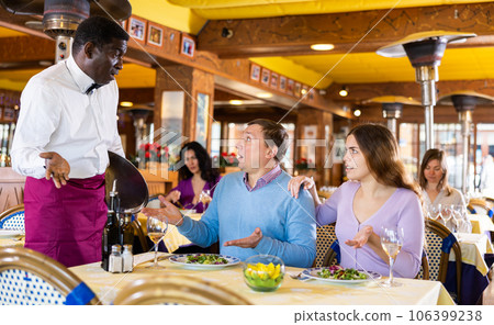 Dissatisfied guests conflicting with african american waiter in restaurant Dissatisfied guests conflicting with african american waiter in restaurant 106399238