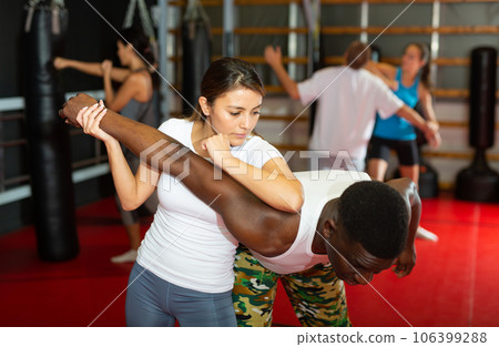 Latino woman is training with man on self-defense course in gym Latino woman is training with man on self-defense course in gym 106399288
