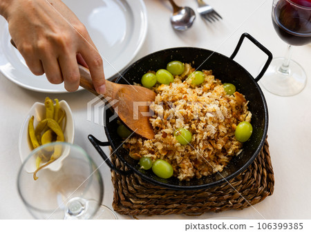 Womens hands with spatula lay out porridge made of bread crumbs, bacon and sausages chorizo - migas Womens hands with spatula lay out porridge made of bread crumbs, bacon and sausages chorizo - migas 106399385
