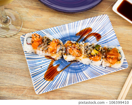 Sushi rolls with crab, cucumber, salmon, avocado seasoned with unagi sauce Sushi rolls with crab, cucumber, salmon, avocado seasoned with unagi sauce 106399410