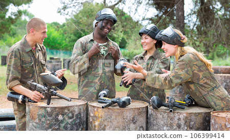 Smiling friends chatting after successful paintball match Smiling friends chatting after successful paintball match 106399414