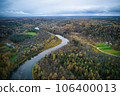 Above aerial shot of green pine forests and yellow foliage groves with beautiful texture of golden treetops. Beautiful fall season scenery in evening. Mountains in autumn colors in golden time 106400013