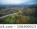 Above aerial shot of green pine forests and yellow foliage groves with beautiful texture of golden treetops. Beautiful fall season scenery in evening. Mountains in autumn colors in golden time 106400023