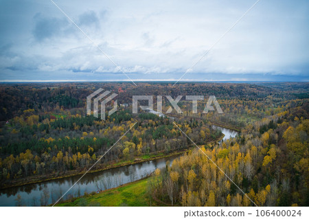 Above aerial shot of green pine forests and yellow foliage groves with beautiful texture of golden treetops. Beautiful fall season scenery in evening. Mountains in autumn colors in golden time 106400024