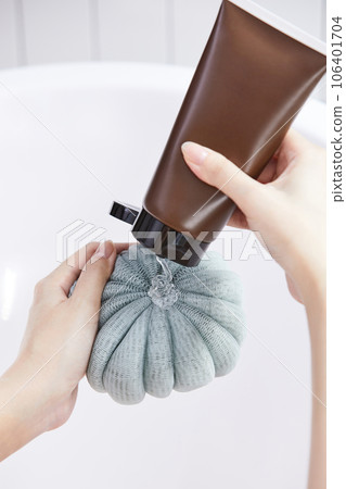 beauty concept photo of korean asain beautiful woman applying shower gel onto a shower pouf. beauty concept photo of korean asain beautiful woman applying shower gel onto a shower pouf. 106401704