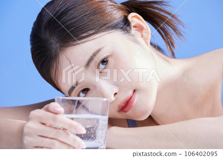 beauty concept photo of korean asain beautiful woman lying on her stomach with a glass cup 106402095